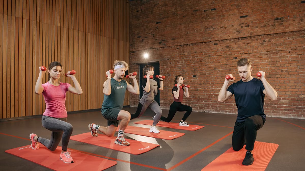 Indoor group workout session with dumbbells focusing on strength and fitness.